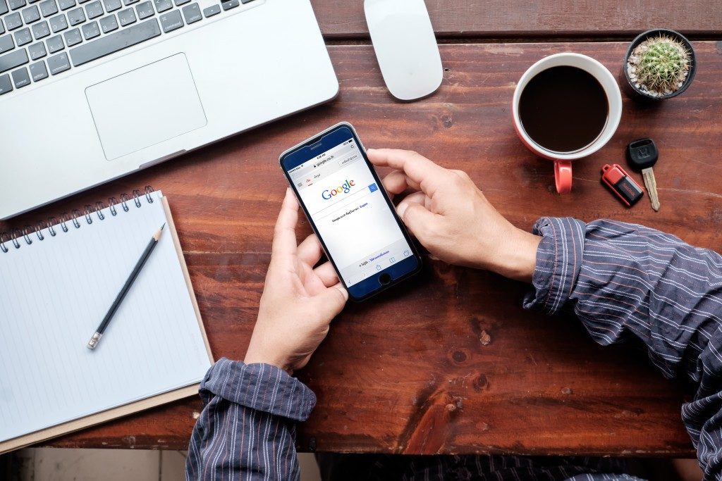 Hands holding on to a smartphone in a work environment