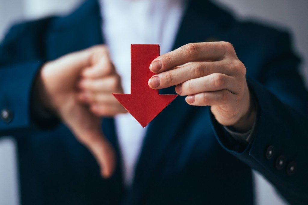 businessman holding a red arrow facing down