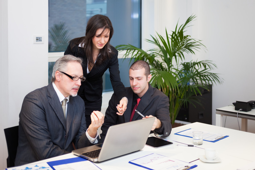 three business people having a discussion in front of a laptop